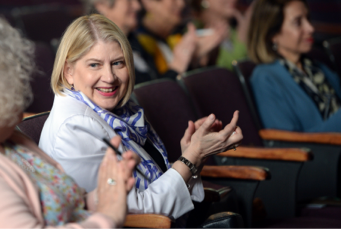 President Zak, sitting in an auditorium seat, applauds